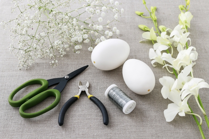 Připravte si všechno potřebné náčiní. Potřebujete nůžky, drátek, vyfouklá vajíčka, kleštičky a květiny. Na obrázku je orchidej a gypsophila. Při ruce mějte také tavící pistoli. Může se hodit. 
