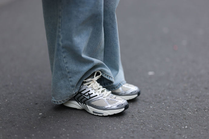 Stříbrné tenisky Nike se hodí ke světle modrým džínům v širokém střihu.
