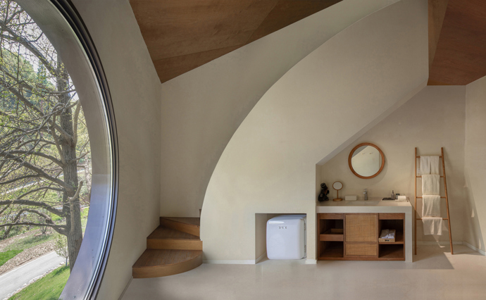 Architekti z Moguang Studio postavili mezi stromy chatu, která neruší, ale přirozeně splyne s lesem. Dům stojí na pilířích, aby nepoškodil kořeny starých stromů, a místo klasických oken má geometrické výřezy, které rámují krajinu.
