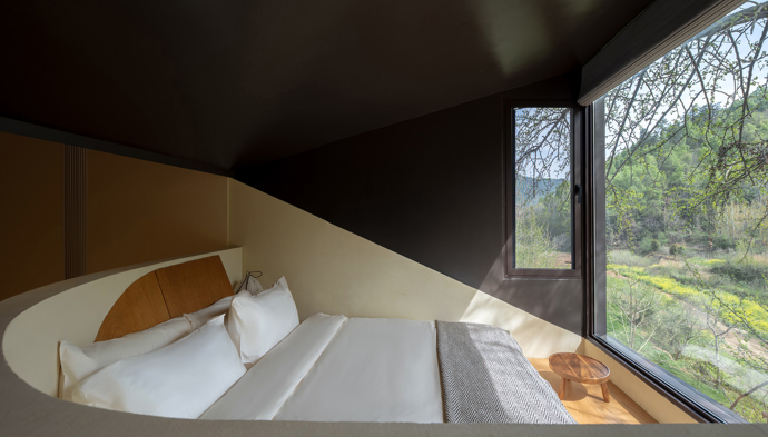 Architekti z Moguang Studio postavili mezi stromy chatu, která neruší, ale přirozeně splyne s lesem. Dům stojí na pilířích, aby nepoškodil kořeny starých stromů, a místo klasických oken má geometrické výřezy, které rámují krajinu.
