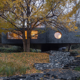 Architekti z Moguang Studio postavili mezi stromy chatu, která neruší, ale přirozeně splyne s lesem. Dům stojí na pilířích, aby nepoškodil kořeny starých stromů, a místo klasických oken má geometrické výřezy, které rámují krajinu.
