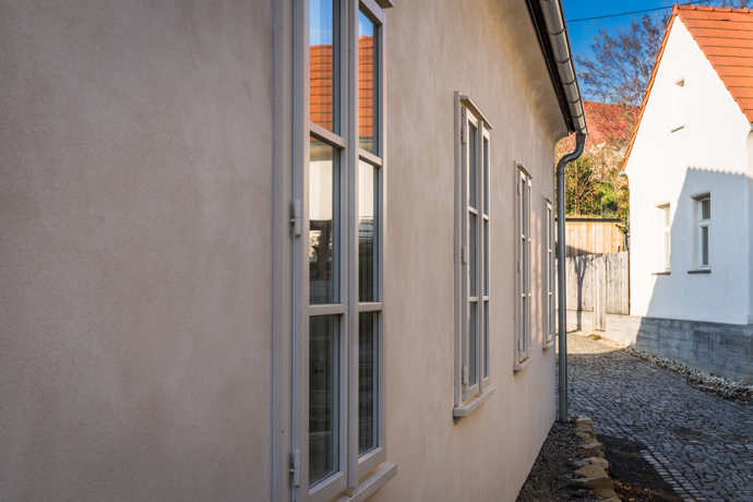 Už když otevřete vrátka, máte pocit, jako byste vstoupili do malované pohádky. Malý bílý domek s kouzelnými detaily, dřevěné trámy, květiny v oknech, klid a žádný spěch. Interiér voní dřevem a poctivou řemeslnou prací, ale nese v sobě i moderní komfort. A co je možná nejdůležitější – všechno tu působí opravdově a srdečně. 
