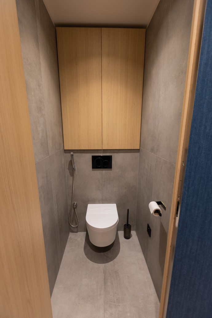 Koupelna a toaleta byly dispozičně i designově přepracovány. Na wc byl doplněný úložný prostor a bidetová sprška. V koupelně byla vana nahrazena sprchovým koutem a pračka a úklidové prostředky byly schované v nově vybudované skříni z kompaktního materiálu. Tato zadní část koupelny je v temném břidlicovém odstínu.
