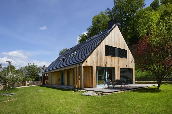 Jednopodlažní obdélníkový dům s podkrovím je pojatý ve formě vracející se ke své jednoduchosti, avšak v moderním stylu. Sedlová střecha, fasáda z neošetřeného modřínu, pastelově modrá okna a dveře, která mírně rozhýbávají neutrální paletu. 
