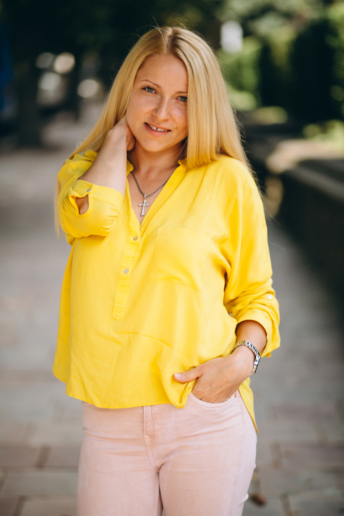 Žlutá halenka dodává outfitu teplý a slunečný nádech. Působí svěže, přirozeně a ladí s parkovým prostředím. Barva oživuje celkový look a tak přitahuje pozornost. Kombinace s jednoduchými doplňky podtrhuje hravost stylu. Celkově outfit vyzařuje pozitivní energii a lehkost
