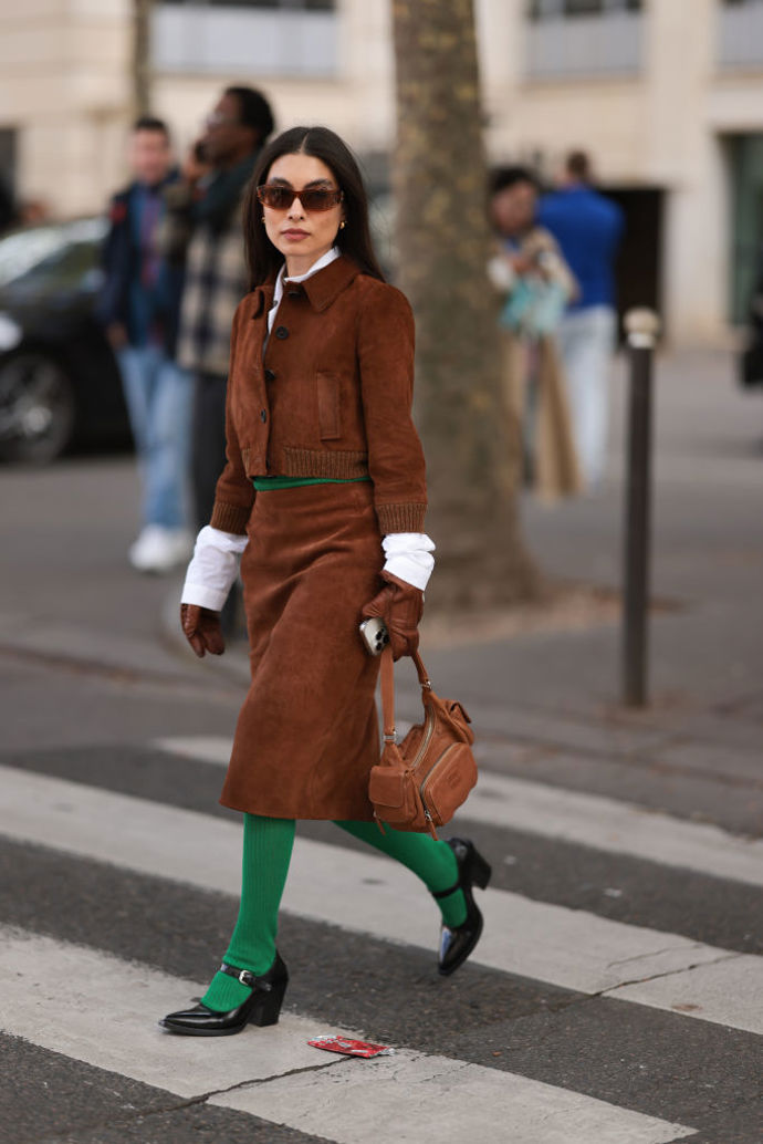 Kontrastní zelené punčochy rozbijí jinak tlumený hnědý outfit.
