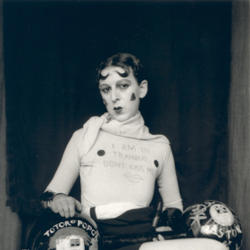 Jeden z mnoha autoportrétů Claude Cahun. Má na sobě tričko s nápisem „Jsem v tréninku, nelíbejte mě.“

