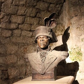 V této drsné alpské pevnosti strávil Toussaint Louverture poslední měsíce svého života. Nápis na podstavci připomíná jeho prorocká slova o tom, že kořeny svobody nikdy nepůjde vyhladit.
