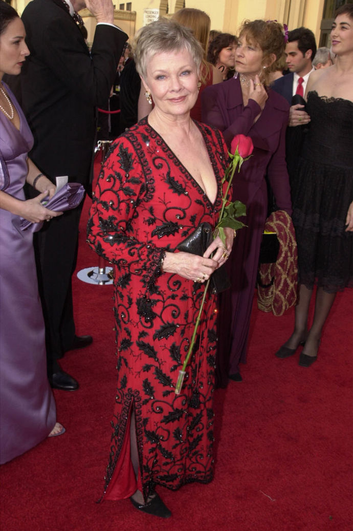 Judi Dench na udílení Oscarů v roce 2001 v červených šatech s černým zdobením.

