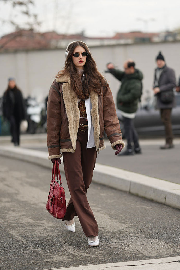 K hnědému outfitu s shearling bundou přidejte zářivě červenou kabelku.
