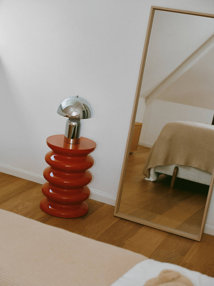 Na červeném vlnitém stolku u zrcadla stojí malá lampa ve tvaru hříbku. Pochází ze stejné edice jako ta v obývacím pokoji. 
