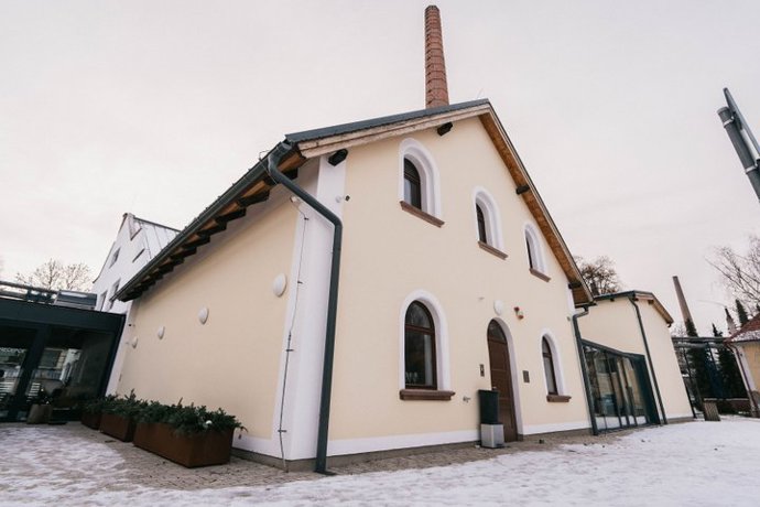 Velkou roli hraje práce se světlem. Prosklené prvky a otevřenější dispozice pomáhají interiér prosvětlit, aniž by narušily jeho charakter. Vedle původních materiálů se objevují nové povrchy, které prostor doplňují. Některé části působí téměř galerijně, jiné si zachovávají syrovější, klubovou atmosféru. 
