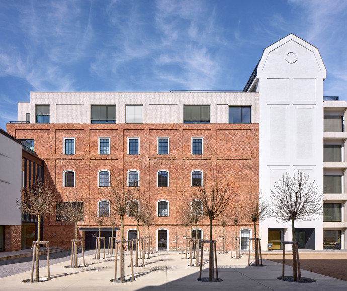Podobně citlivý přístup architekti zvolili i u bývalé správní budovy. Ta získala nový cihelný sokl a světlou omítku. 
