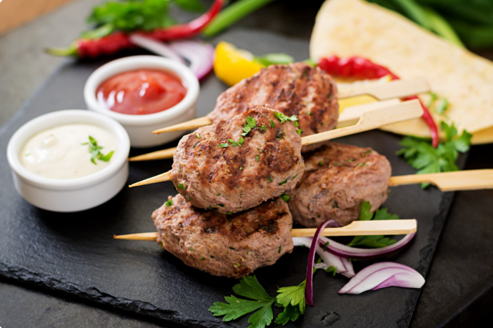 Kofta
Kofta pochází z oblasti Blízkého východu, Turecka a Balkánu. Připravuje se z mletého hovězího nebo jehněčího masa ochuceného česnekem, cibulí, kmínem či koriandrem. Masové válečky nebo kuličky se grilují nebo pečou a podávají se s chlebem pita, rýží a jogurtovým dipem.
