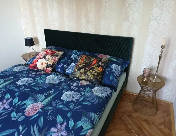 Elegantní zelená ložnice se sametově čalouněnou postelí.
