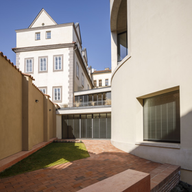 Na místě bývalé dílny, ukryté za historickou zdí a zarostlou zahradou, dnes stojí bytový dům s galerií, který propojuje bydlení s uměním. Architekti Ladislav Lábus, Lukáš Grasse a František Košař navrhli stavbu, která nevystupuje do popředí, ale pracuje s proporcemi, materiály i světlem tak, aby respektovala charakter Malé Strany. 

