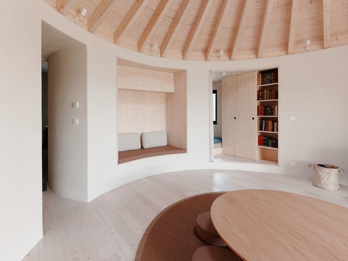 Tvar tradiční kruhové jurty uchvátil mladý manželský pár, který si chtěl postavit víkendový domek. Architekti jim přání splnili a vytvořili jednoduchou dřevostavbu, která zadání dokonale splňuje. 
