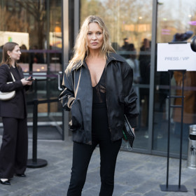 Kate Moss na přehlídce Stelly McCartney v březnu 2025 – pod objemnou koženou bundu oblékla top s krajkovými průstřihy, doplnila ho legínami a pantoflemi na klínku
