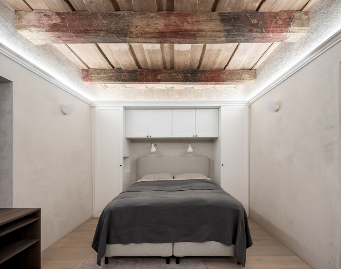 Když architekti poprvé vstoupili do domu, bylo jasné, že nejde o obyčejnou rekonstrukci. Objekt ukrytý v historických hradbách si zachoval mnoho původních prvků, jako je kamenné zdivo, klenuté stropy v přízemí, malované dřevěné stropy v patře i původní kachlová kamna. 
