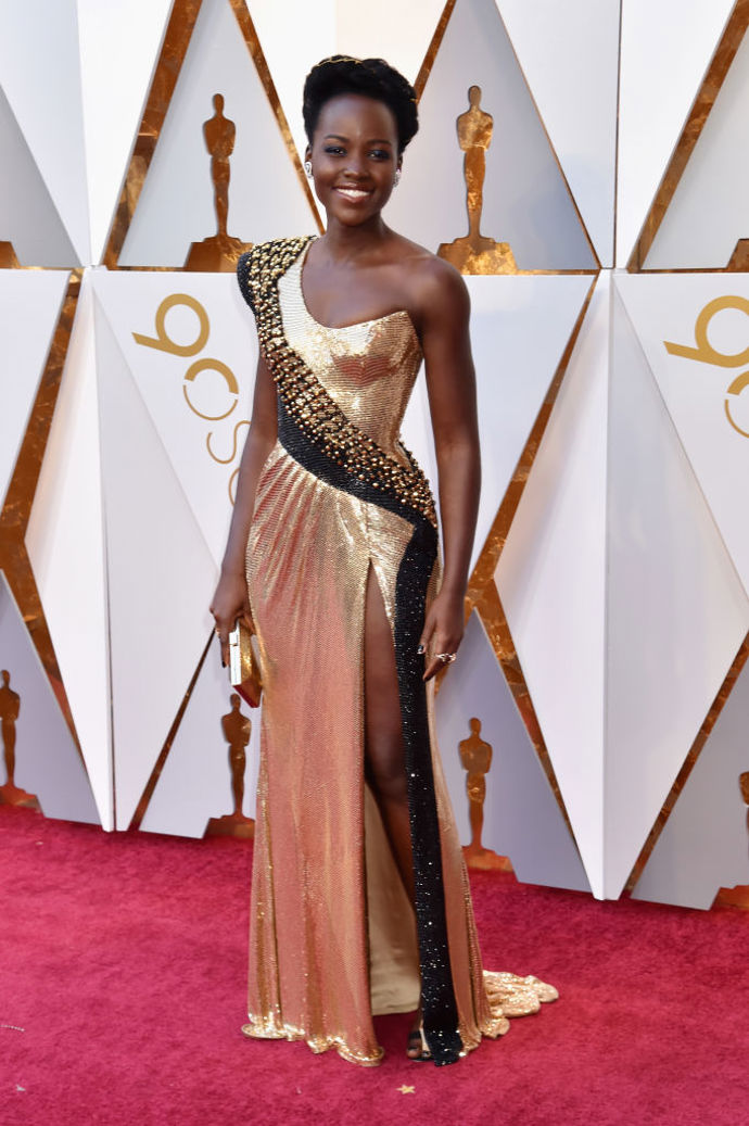 Lupita Nyong'o v šatech na zakázku od Atelier Versace s kabelkou Versace, šperky Niwaka a botami Alexandre Birman
