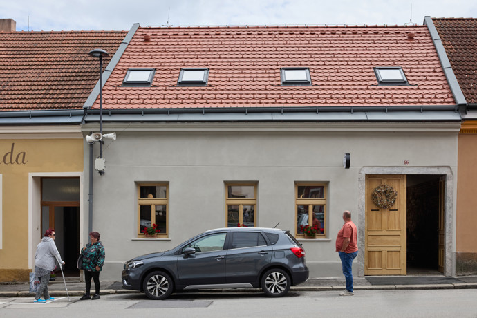 Hosté mohou posedět na dlouhé jasanové lavici a modrých židlích, které dodávají prostoru svěží energii. Kavárna plynule přechází průjezdem až na dvůr, kde vznikla betonová lavice a venkovní posezení. Prostor se tak přirozeně rozšiřuje a otevírá směrem ke komunitnímu životu městečka.

