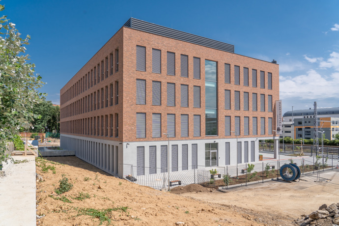 Kompaktní objem stavby nepůsobí okázale, spíš přirozeně zapadá do okolní struktury Vysočan, kde se postupně mísí industriální minulost s novou městskou vrstvou.
