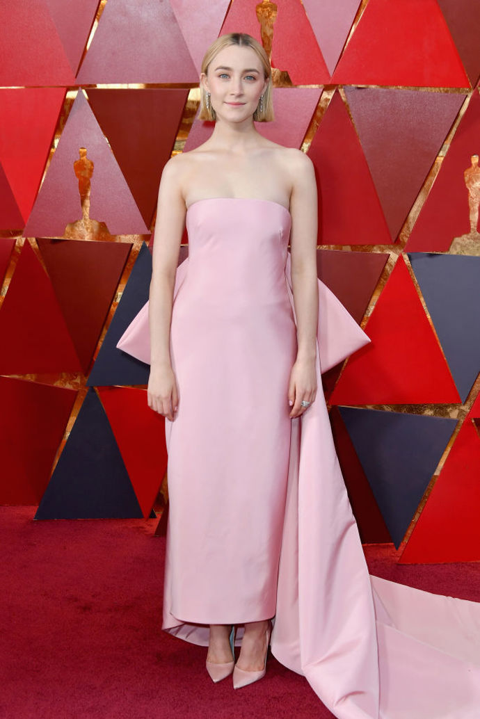 Saoirse Ronan v šatech od Calvina Kleina, botách Christian Loubotin, špercích Cartier a s kabelkou Jimmy Choo. Saoirse byla nominovaná za hlavní roli ve filmu Lady Bird.

