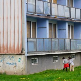 Kolem opuštěných domů si hrají děti.