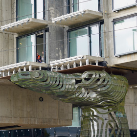 Stavbu podpírají obří ruce.