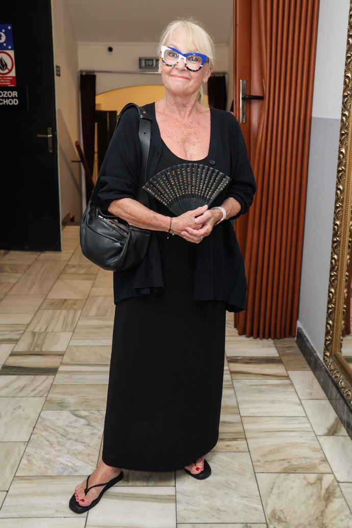 Herečka Kateřina Macháčková si potrpí na extravagantní brýle, zbytek outfitu proto volí v tlumených barvách. Do kabelky ovšem nezapomněla přibalit praktický vějíř.