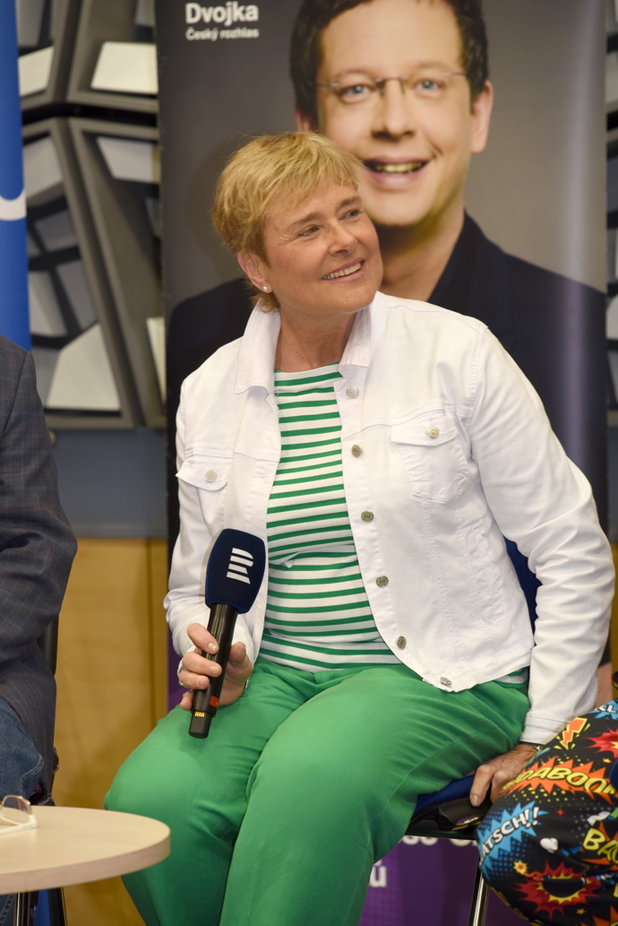 Oblékla také zelené kalhoty, zeleno-bílé tričko a bílou bundičku.