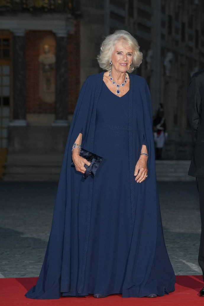 Camilla zvolila jednoduché šaty s impozantní pelerínou. Minimalistický střih bez přílišné zdobnosti dovolil Camille doplnit je úžasnou sadou rodinných klenotů.