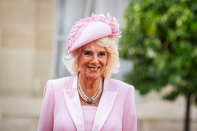 Růžové plášťové šaty doplnil stejně stylový klobouček a také impozantní klenot. Jeden ze šperků, který Camilla nosí nejčastěji, čtyřřadý perlový náhrdelník s diamantovou sponou.