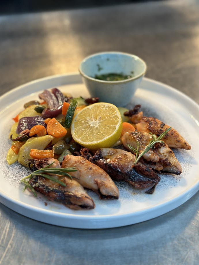 Hlavním chodem jsou grilované kalamáry, gremoláda s citrónem, petrželí a česnekem, zelenina pečená v troubě na bílém víně.