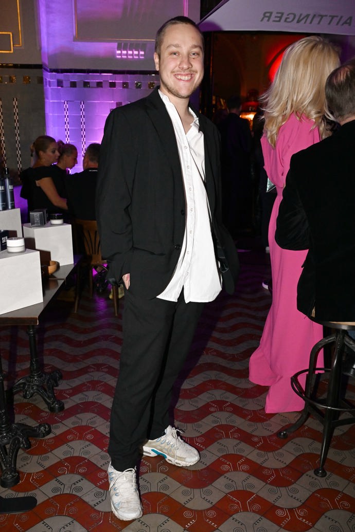 Bratr kuchařky Kamu Adam Rundus oblékl černý pánský oblek, který doplnil bílými teniskami a ležérní bílou košilí.