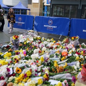 Na místo před arénou fanoušci nosí květiny.