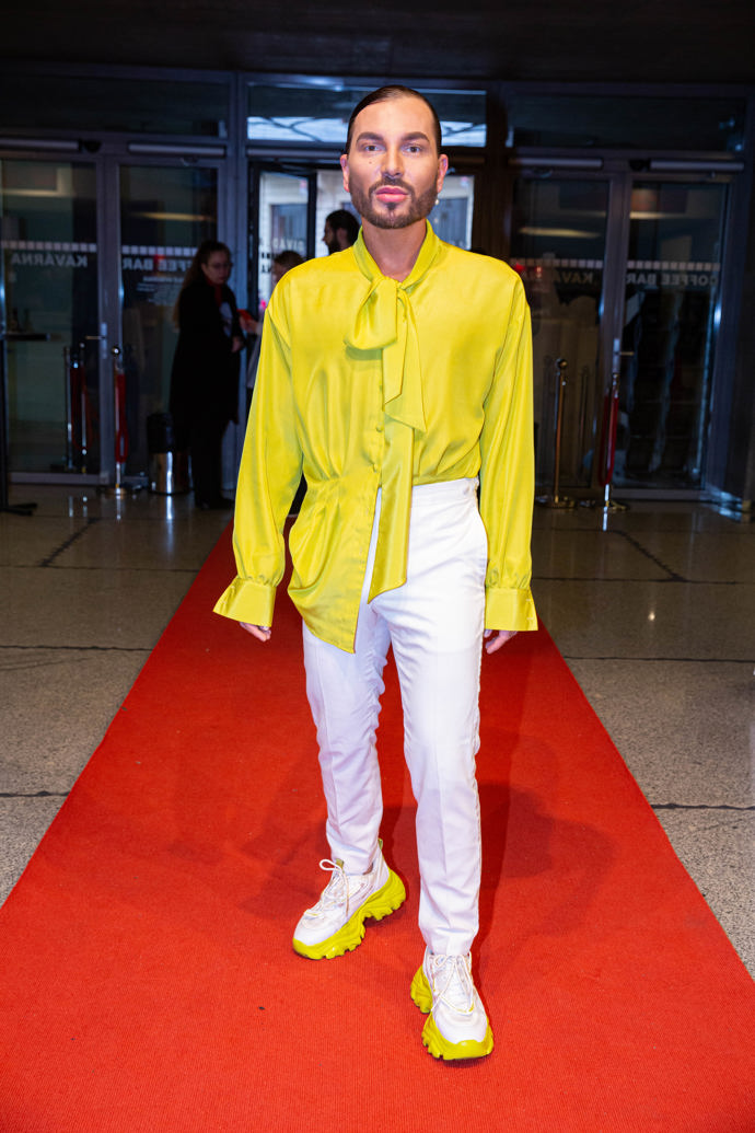 Stylista Sam Dolce v bílých kalhotách a limetkovém topu na premiéře projektu Vivaldianno. 