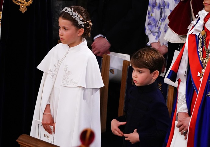 Určitě nejimpozantnější outfit vynesla Charlotte na korunovaci dědečka Karla III. Do Westminsterské katedrály vstoupila oblečená do hedvábných slonovinových šatů s pelerínou od Alexandera McQueena. Na hlavě měla čelenku s 3D florálními motivy, na níž Alexander McQueen spolupracoval s kloboučnicí Jess Collett, a na nohou pak Charlotte boty typu Mary Jane značky Papouelli (2 350 Kč).