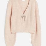 Pulovr s hlubokým výstřihem zdobený štrasovou mašlí. (H&M, 349 Kč) 