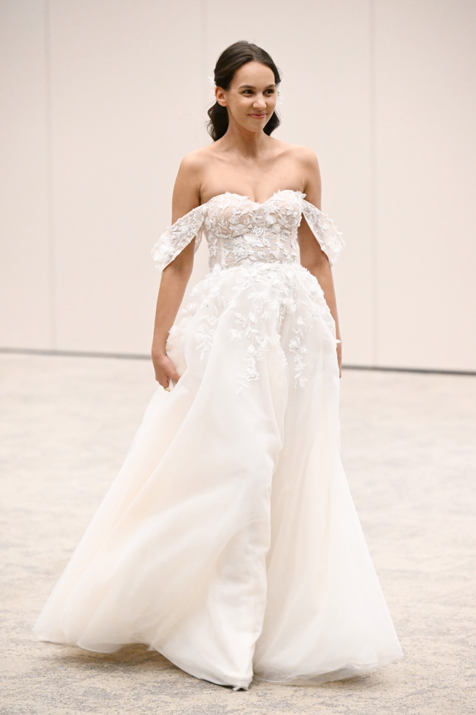 Svěšená ramínka doplňující krajkový korzet klasických svatebních šatů z tylu ozdobených něžnými krajkami. Absolutní svatební klasika i horký trend současnosti.