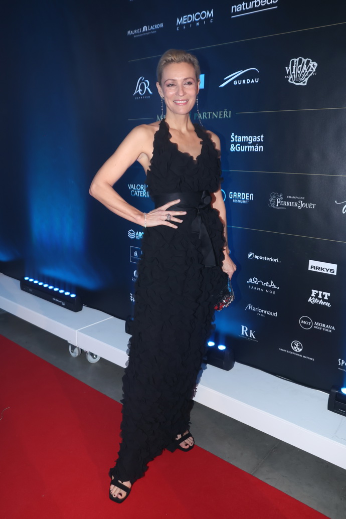 Modelka Martina Šmuková v decentní černé róbě s odhalenými pažemi.