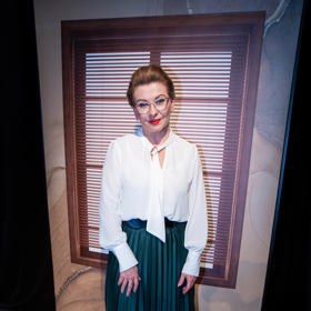 Herečka Dana Morávková nosí tmavě zelenou plisovanou sukni v kombinaci s bílou halenkou. 