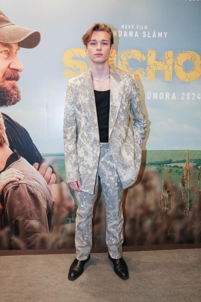 Mladý herec a zpěvák Tomas Sean Pšenička oblékl na pražskou premiéru šedo-bílý kalhotový kostým, pod který přidal jen černé basic tričko a nezbytný jednořadý perlový náhrdelník. 