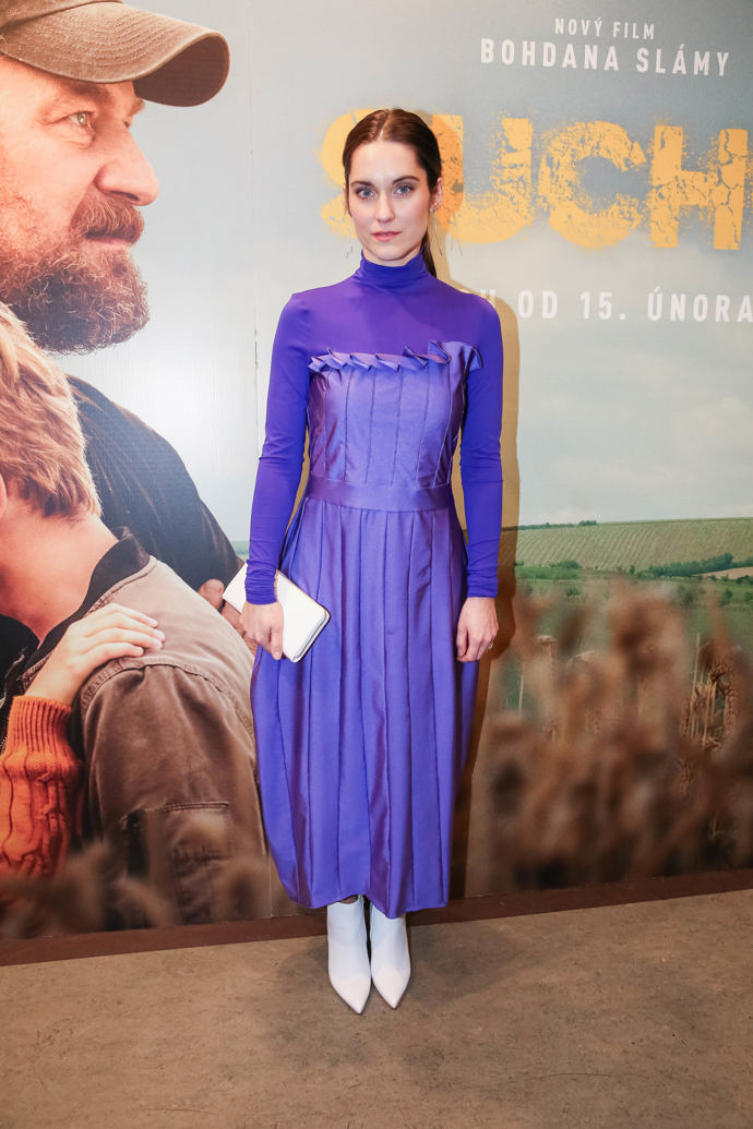 Herečka Judit Pecháček vynesla na pražskou premiéru fialové šaty z dílny Josefiny Bakošové. Doplnila je bílými botami a bílým psaníčkem.