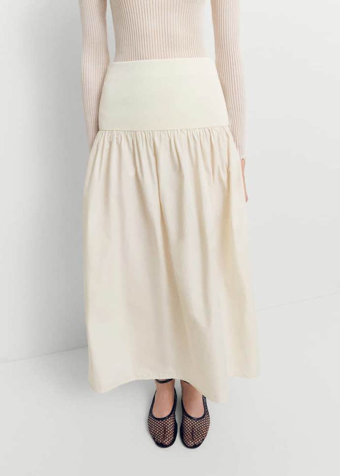 Stejný střih nabízí i sukně značky mango s pružným sedlem posouvajícím linii pasu do šíře boků. (2 299 Kč)