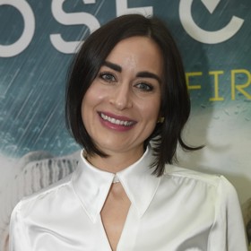 Široký střih nohavic umocněný vysokým pasem a nápadným páskem zkombinovala s kontrastní saténovou blůzou. Tu ozdobil netradiční tvar výstřihu.