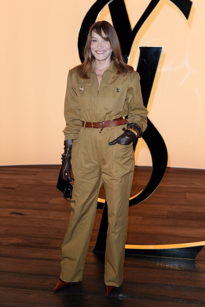 Bývalá francouzská první dáma Carla Bruni (56) rovněž dorazila v na přehlídku ve velmi šik outfitu - olivově zeleném overalu, výrazných hnědých kožených rukavicích a třešňově zbarvených lodičkách na moderním kotěcím podpatku.