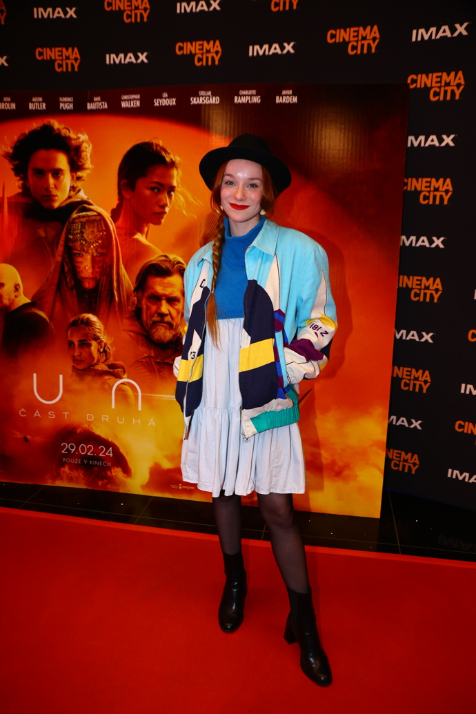 Herečka Yvona Stolařová z filmu Aristokratka ve varu oblékla do kina nápadný barevný bomber, černý klobouk a bílé šaty s modrým pleteným topem.