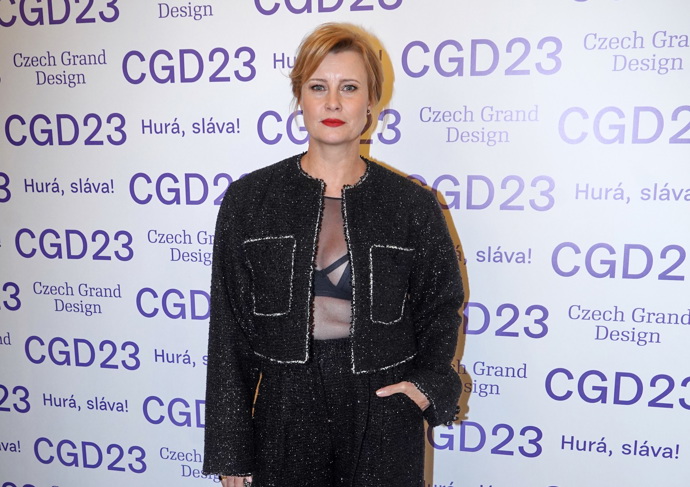 Kalhotový kostým z buklé s třpytivými nitkami a lemováním doplnila rafinovaným prvkem v podobě průhledného topu odhalujícího podprsenku.