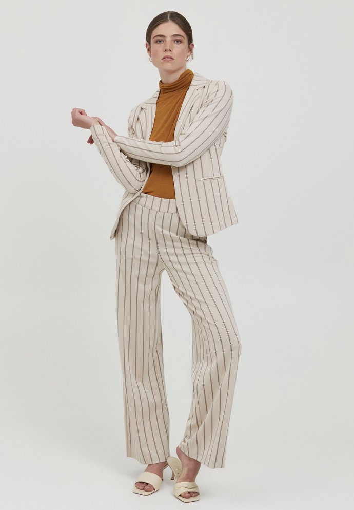 Pokud si máte mezi trendy vybrat nejvýraznější vzor kalhotového obleku, pak jsou to jednoznačně svislé proužky.